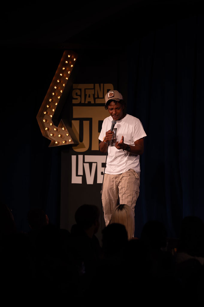 Lamar Mitchell J.R. holding a microphone during a stand-up set onstage.