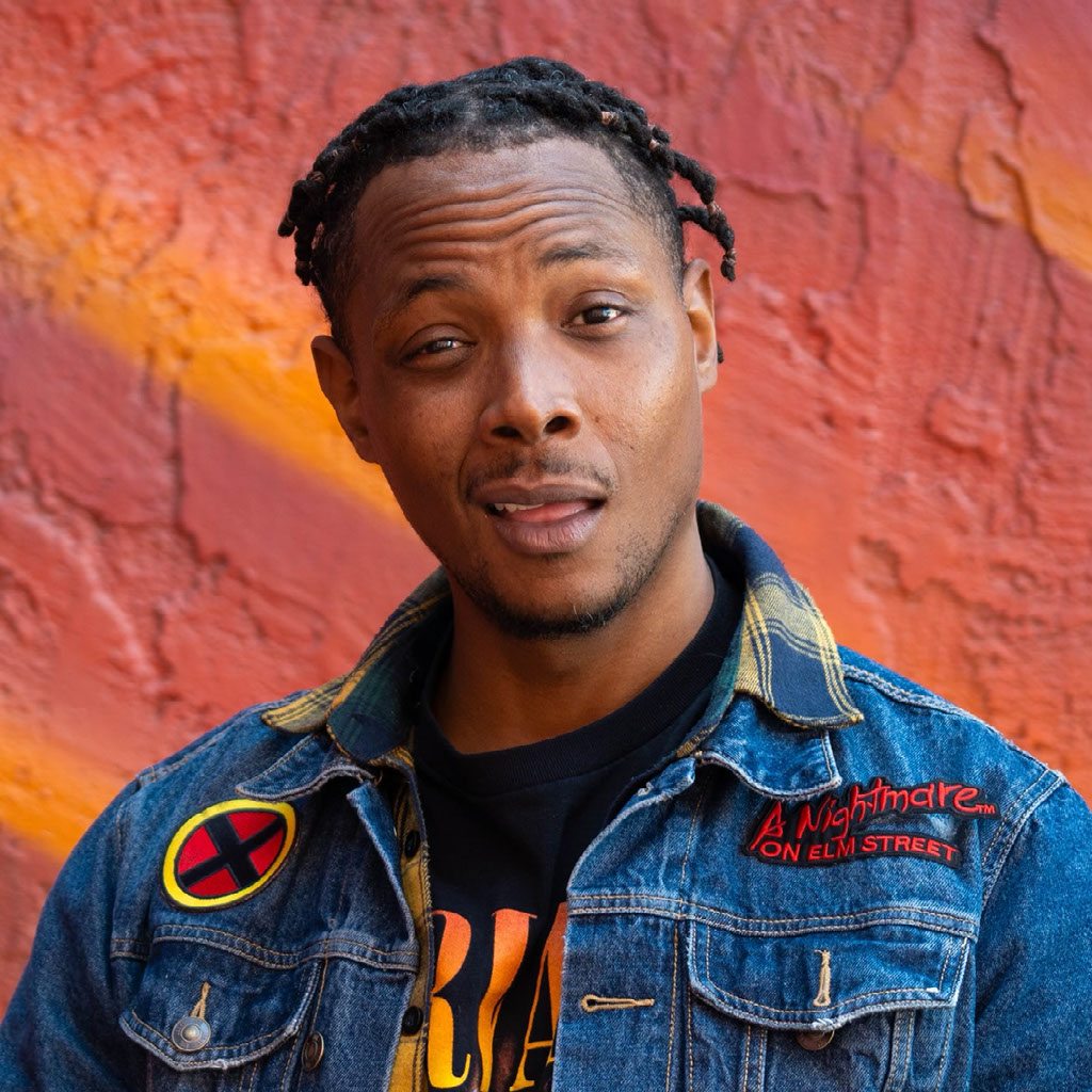 Lamar Mitchell J.R. in a denim jacket, photographed against a warm red wall.
